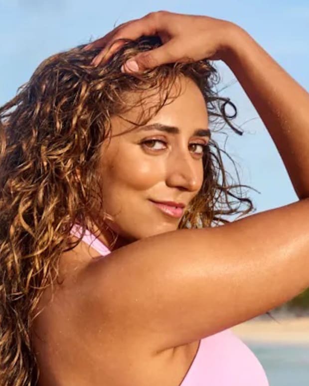 Sarafina El-Badry Nance poses in front of the ocean in a pink bikini and wet curly hair.
